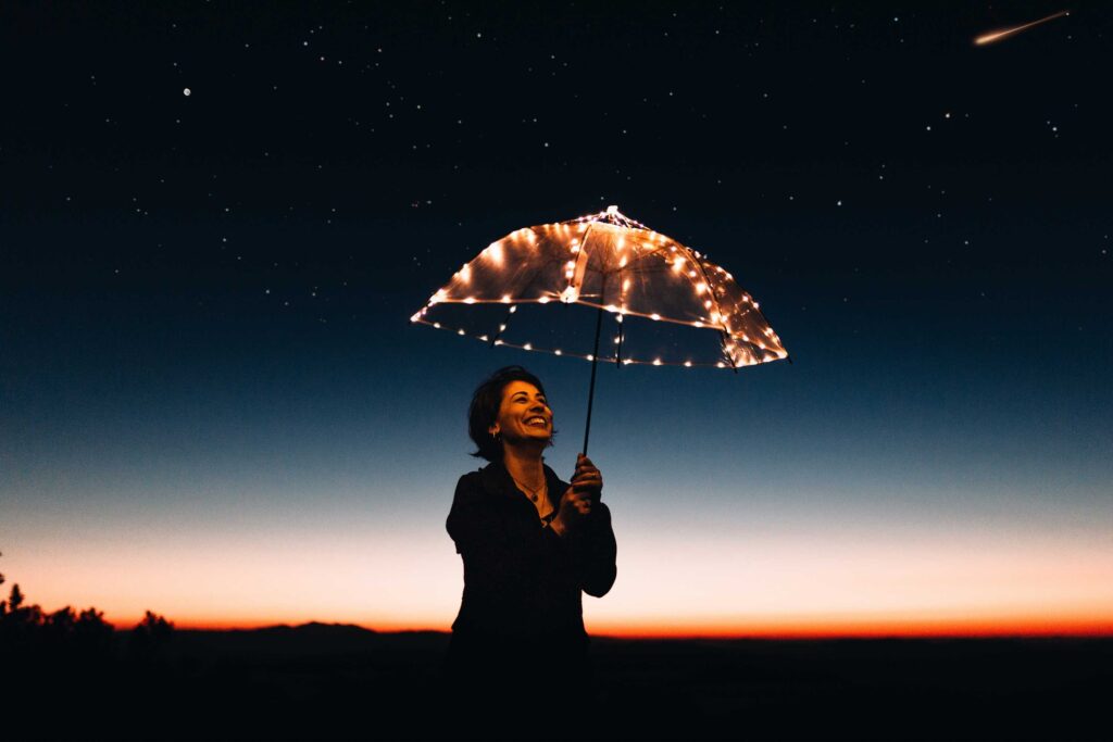 Woman with firelight umbrella at dusk. Finding light in the winter darkness